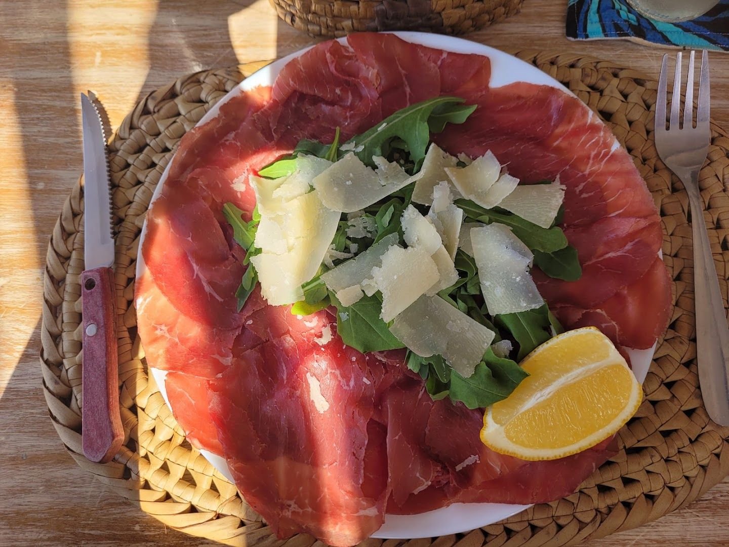 Bresaola with rocket, shaved grana and a lemon wedge in the sun