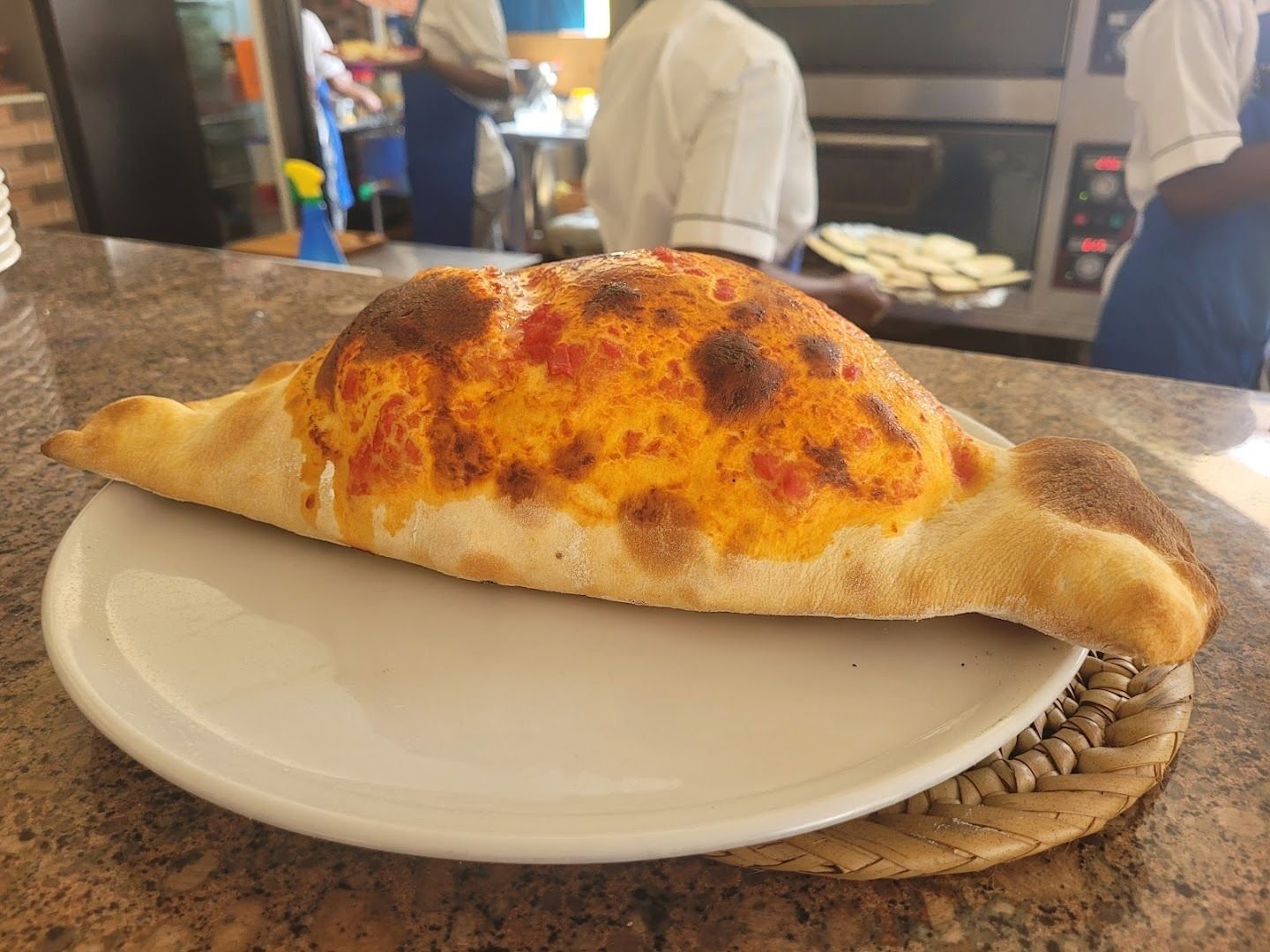 A whole baked calzone with a blistered, golden crust