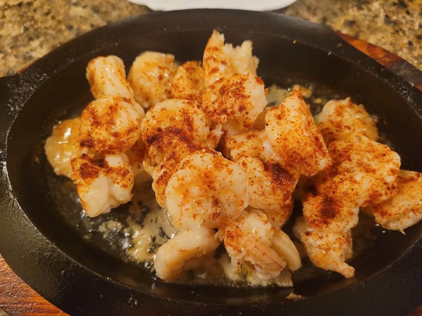 Garlic shrimp sizzling on a hot plate at Jolly's kitchen counter