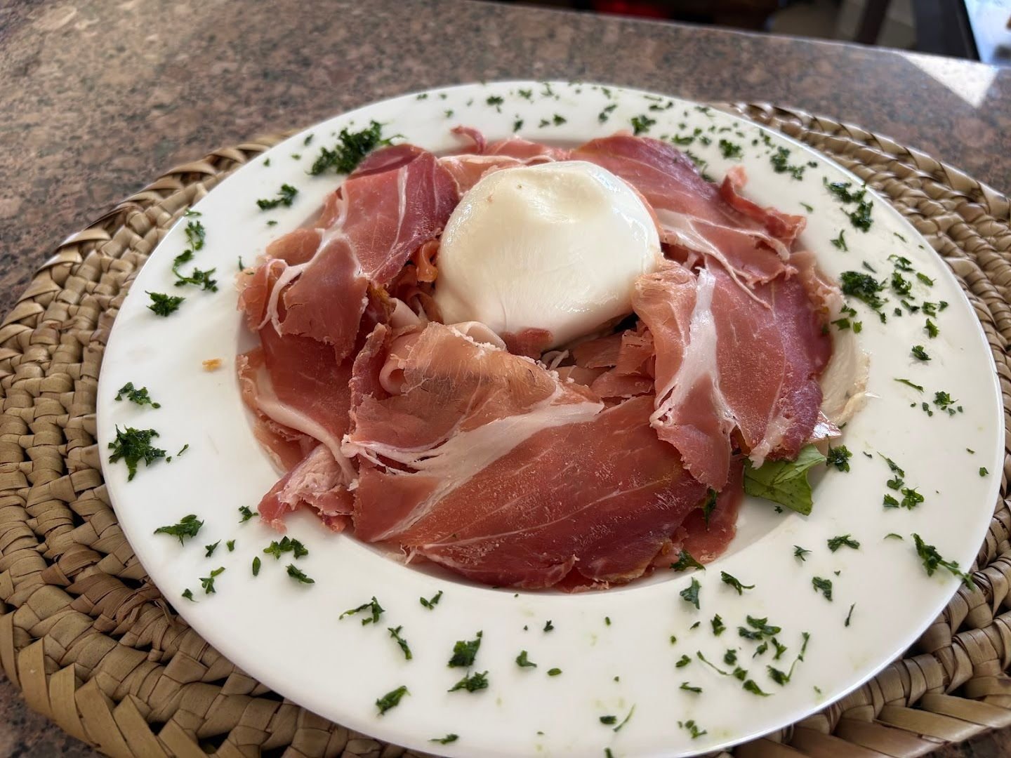 Sliced prosciutto crudo fanned around a whole ball of fresh mozzarella